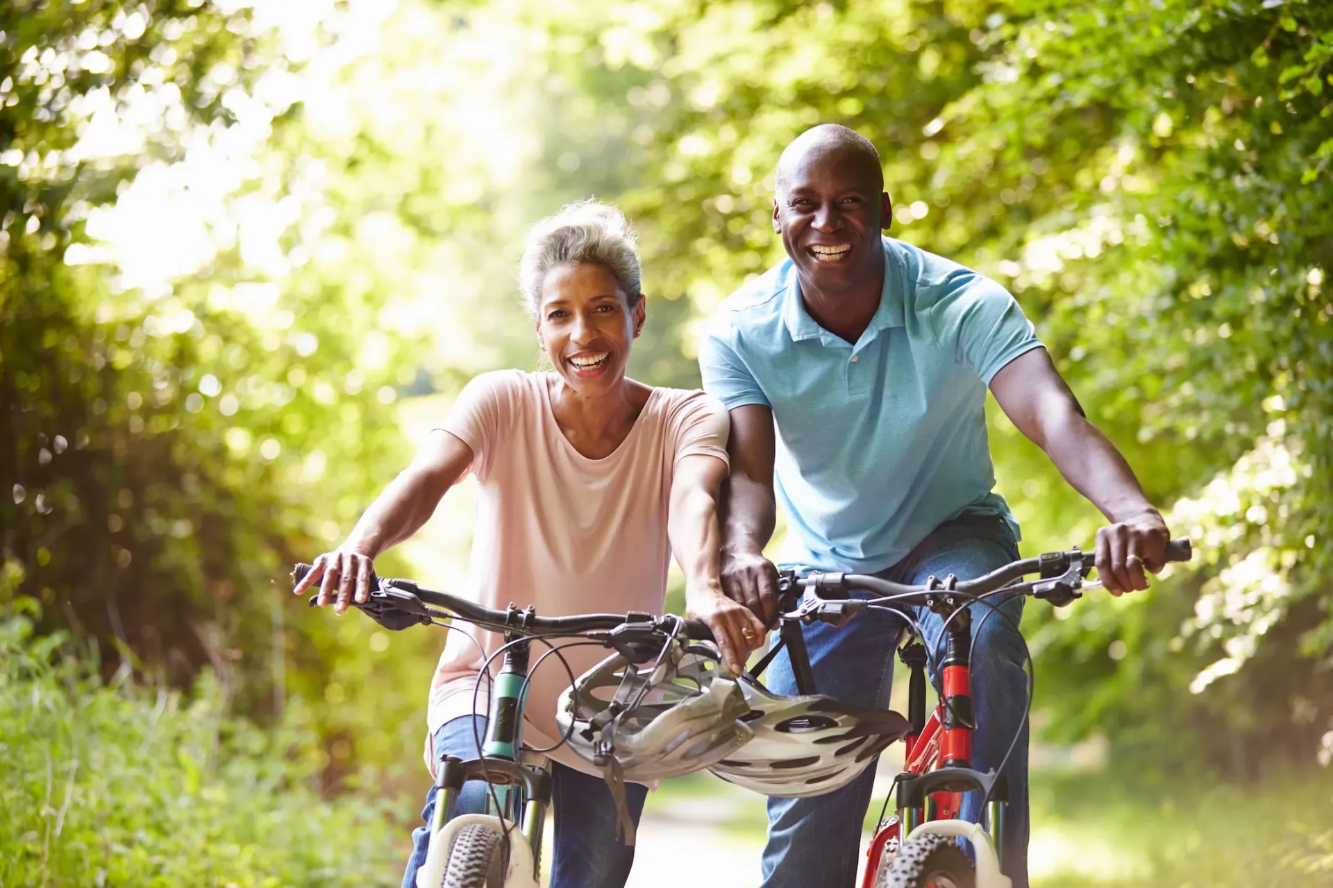 A smiling couple riding bicycles together outdoors
